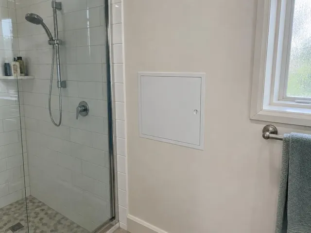 Bathroom shower wall with a neat white access panel beside a window in Harris Park